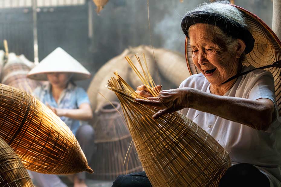 Asiatische Frau am flechten von Bambus-Korb