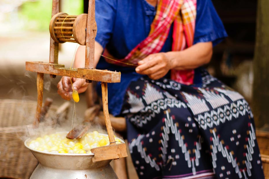 Traditionelle Herstellung von Zuchtseide, die Kokons werde dabei in kochendes Wasser gegeben.