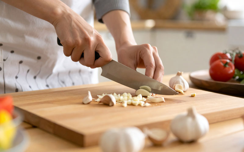 Schneiden von Knoblauch auf Holzschneidebrett